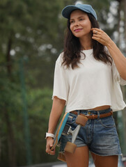 A woman is walking at the city park while carrying a skateboard in her hands