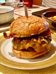 Close-up of the 2024 award-winning burger featuring a juicy beef patty, melted cheese, crispy bacon, and a soft brioche bun, served on a decorative plate.