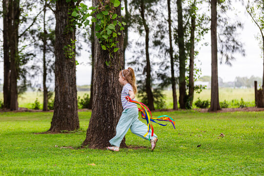 Girl with rainbow streamers running around outside in country