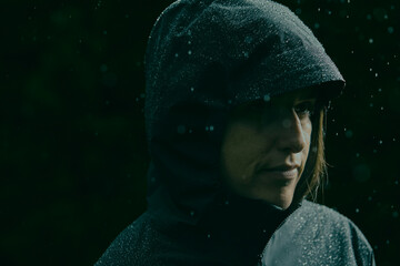 Person in a hooded rain jacket with water droplets, standing in rain © Cavan