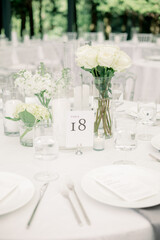 Elegant wedding table with white flowers, candles, and table number.