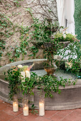 Ornamental fountain with cascading greenery, candles, and flowers.