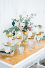Elegant cocktail glasses with lime and mint, beside floral decor.