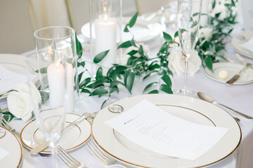 Elegant wedding table setting with greenery, candles, and fine china.