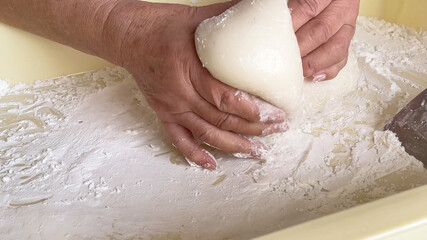 日本の正月行事　つきたての餅を手で小分けにするおばあちゃん