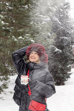 a positive woman, 50 years old, in winter clothes, with a mug of