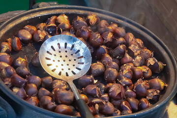fire-roasted chestnuts folded in a pan for cooking over a fire