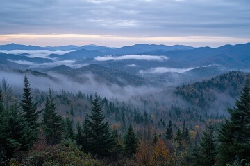 Obraz premium A wide-angle view of a cloudy sky over a mountain range, with soft mist and fog rolling over the peaks