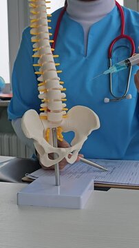 Neurologist doctor holds imitation of spine with intervertebral hernia. Doctor makes paravertebral blockade for spinal hernia and inflammation