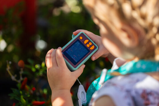 Young child outside with kids digital camera taking a photo of plant in garden