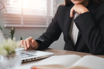 Professional Businesswoman Working on Laptop in Modern Office with Natural Light and Open Notebook
