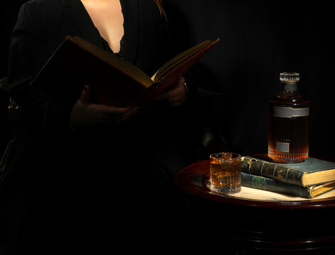 Femme assise lisant un vieux livre pr&egrave;s d'une table basse antique recouverte de vieux ouvrages