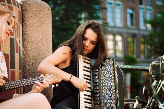 Two women play music on the street, ukulele and accordion, musicians