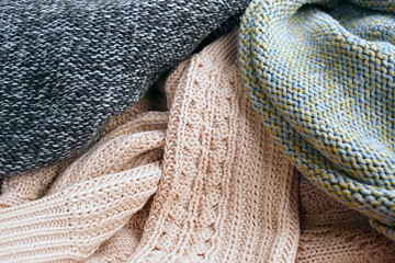 Close-up textures of knitted clothes: black and white fabric in the purl stitch technique, fabric in a combined technique made of pink yarn, the back of a sweater in the stocking stitch technique.