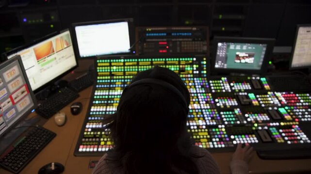 Rear footage of a technician in a T.V master control room during a live broadcast