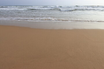 waves crashing on shore of sandy beach on a cloudy day