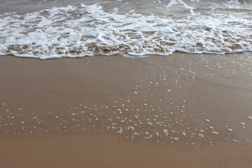 waves crashing on shore of sandy beach on a cloudy day