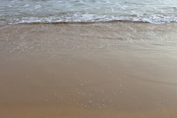 waves crashing on shore of sandy beach on a cloudy day