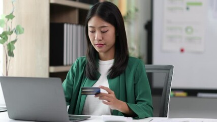 Making secure online payment with credit card. Young woman in office using a laptop and credit card to make an online payment.
