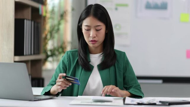 Woman analyzing finances and credit card debt. Stressed businesswoman in office reviewing financial statements, checking credit card balance, and contemplating debt management. Financial planning.