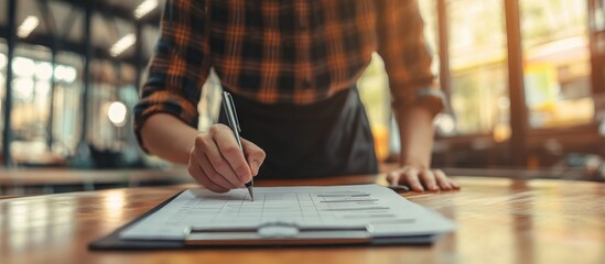 Person filling out paperwork at a wooden table.