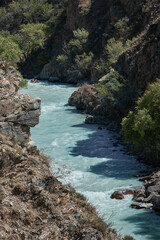 Fototapeta premium A river winds through a rocky canyon, surrounded by lush greenery, creating a beautiful, picturesque scene