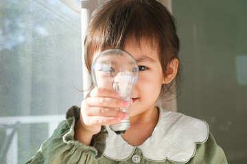 Child joyfully holding a light bulb.