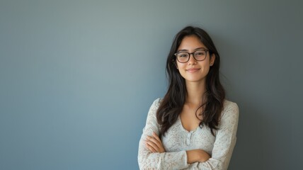 Obraz premium Confident Young Asian Woman with Glasses Standing Against a Plain Background in Casual Attire