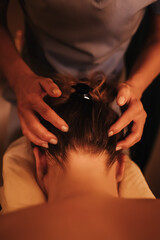 Fototapeta premium The hands of a chiropractor are massaging the neck of a young woman lying on a massage table. Physiotherapy treatment concept, neck pressure point. Wellbeing. No focus blurred. Part of the series.