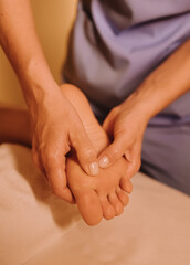 Fototapeta premium The hands of a chiropractor are massaging the leg of a young woman lying on a massage table. Physiotherapy treatment concept, neck pressure point. Wellbeing. No focus blurred