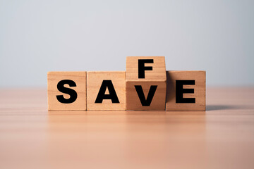 Wooden block cube change between save and safe wording for money saving to safe investment concept.