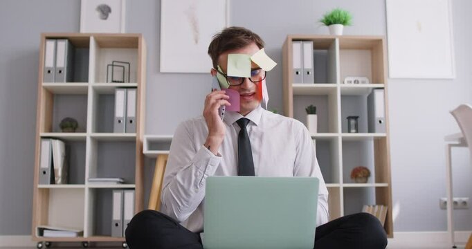 Tired stressed young business man working at desk with laptop talking by mobile phone on workplace in office and starting meditate practicing yoga. Overload and overworked concept. 4k video.