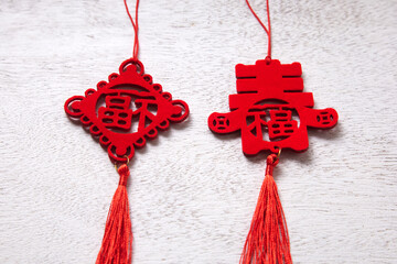 Red Chinese knots with traditional symbols and tassels, on a white wooden background.