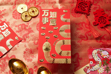 A red envelope with gold accent surrounded with oriental object on a oriental-textured napkin background.