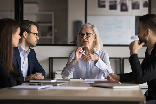 Businesswoman, company boss explains contract details to shareholders, sit at conference table, make speech, provide information, share opinion and strategy, engaged in teamwork activity. Negotiations