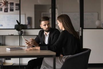 Two young Caucasian teammates involved in dialogue in meeting room, to sharing ideas, creative...
