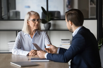 Two colleagues discussing project marketing strategy in office. Professional insurance agent holds...