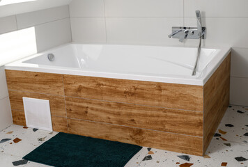 Duża zabudowana wanna płytkami ze wzorem drewna w białej łazience czystość i higiena 
