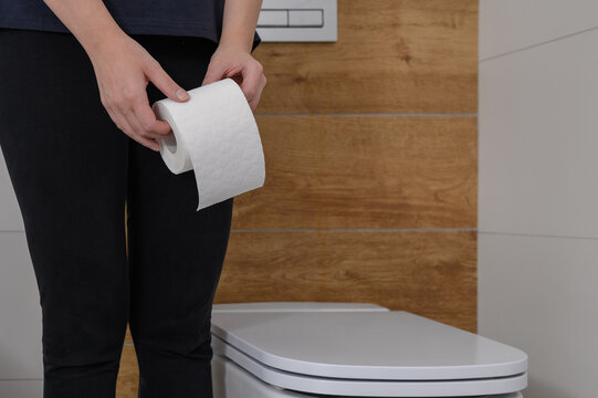 Kobieta w toalecie trzyma papier toaletowy w dloniach