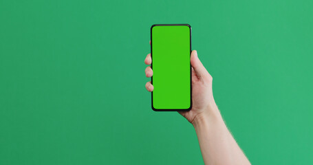 Young man hand hold smartphone with green screen on green background