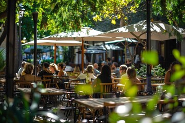 Outdoor cafe with people enjoying a sunny day under large umbrellas, surrounded by greenery and natural light.