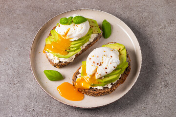 Toast with avocado, soft cream cheese, rye bread and poached Egg. Wholemeal open sandwich for healthy breakfast concept.