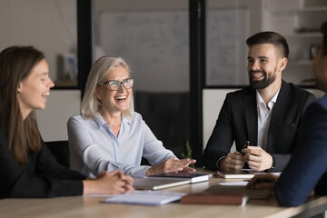 Laughing teammates, diverse professionals negotiating in modern meeting room, smile, share ideas,...