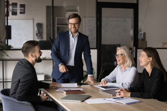 Happy business team participate in meeting, laughing, lead talk in light-hearted and positive atmosphere, sharing creative solutions and ideas enjoy productive, collaborative and successful teamwork