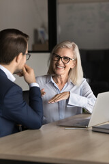 Smiling middle-aged professional female manager, bank advisor talking to client at business...