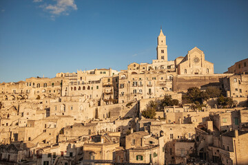 Fototapeta premium A panoramic view of the historical world heritage city of Matera, Puglia, Italy, la città dei sassi, with its cave houses, in warm afternoon light