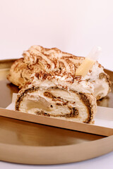 pieces of meringue roll sprinkled with chocolate with condensed milk syringe isolated on a golden tray