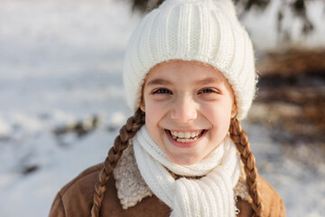 A little girl of 8 years old smiles with a sincere smile. I am glad that winter is coming