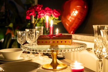 Close up of festive table with flowers in vase, candles and a gift on valentine's day.
