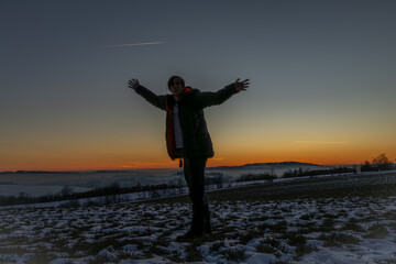 Winter frosty view for sunset over snowy field with silhouette of man